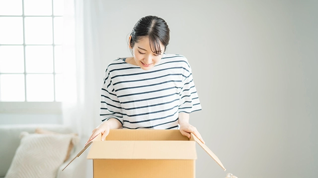 韓国の通販サイトから届いたコスメの箱を開封し、中身や梱包状態を確認している女性